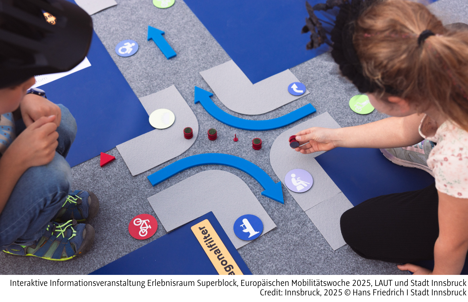 Zwei Kinder die auf einem Plan einer Straße Bausteine legen