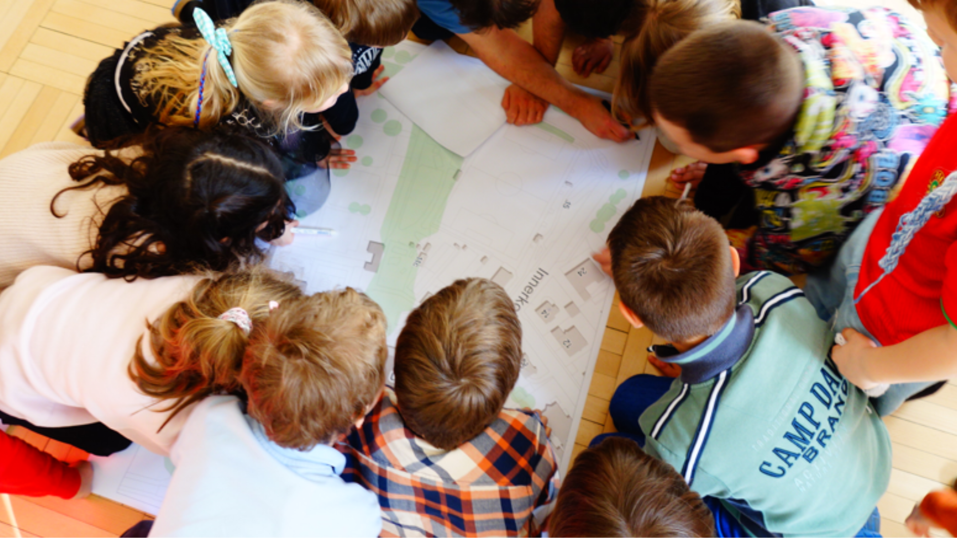 Kinder der Schule in einem Kreis über einen Plan gebeugt.