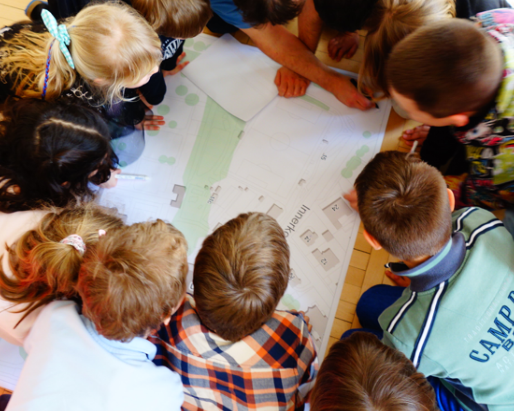 Die Kinder der VS Fischerstraße im kreis um den Plan des Beseleparks